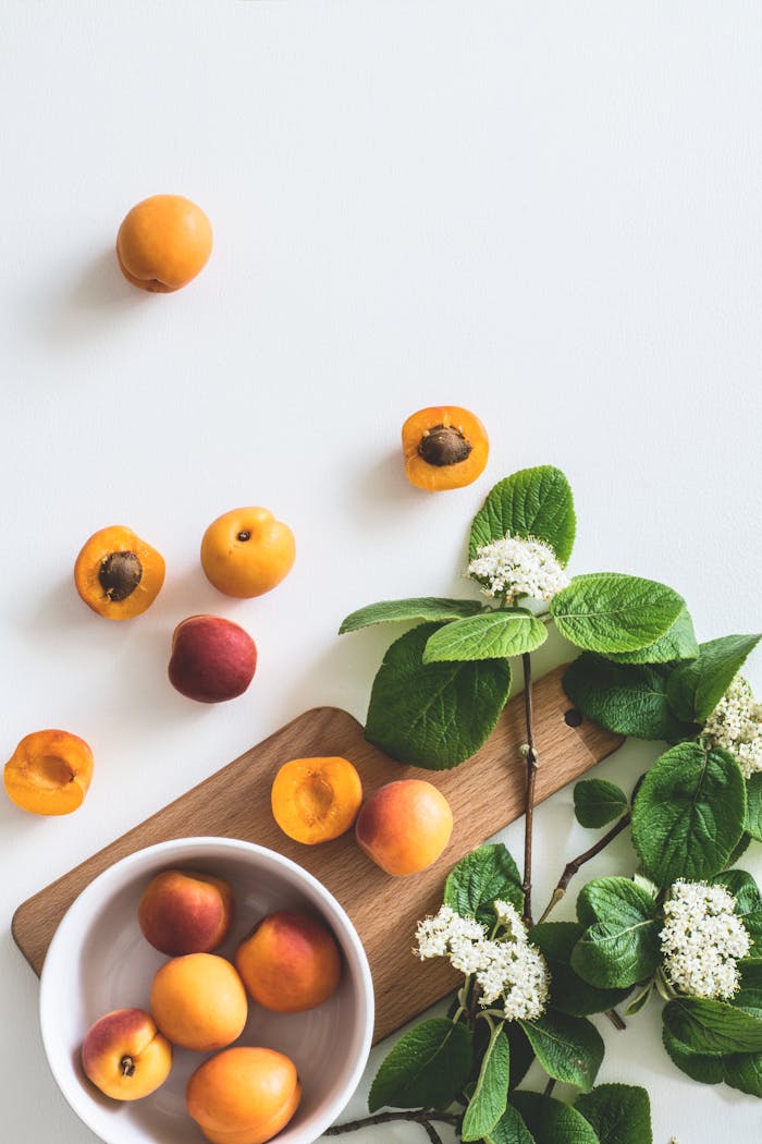 about-02 A flat lay of fresh apricots and blossoms on a board showcasing summer freshness.