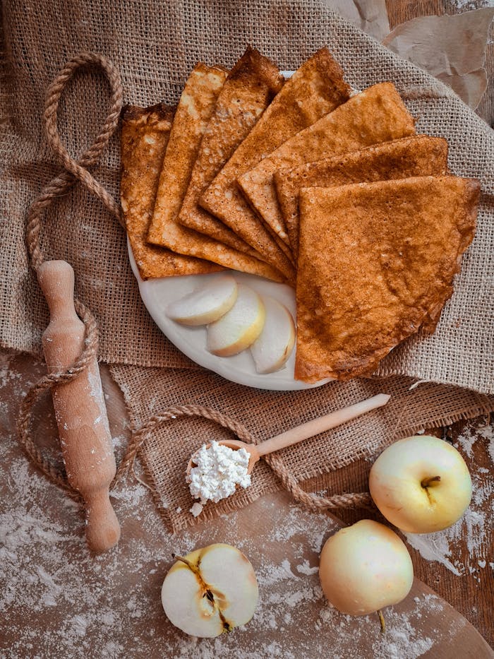 about-01 Flat lay of rustic crepes, fresh apples, and cottage cheese on burlap, perfect for autumn mood.